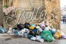 Montón de basura tirada en la calle bajo una pared con grafiti 